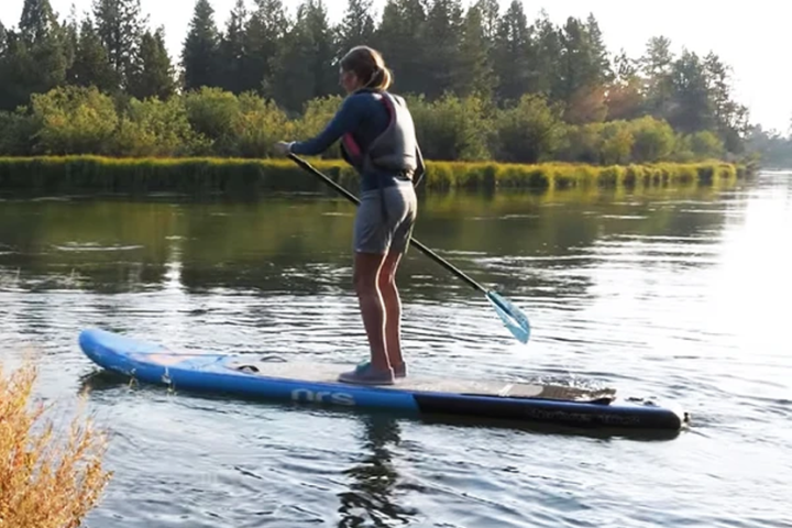 a person riding on the back of a boat next to a lake